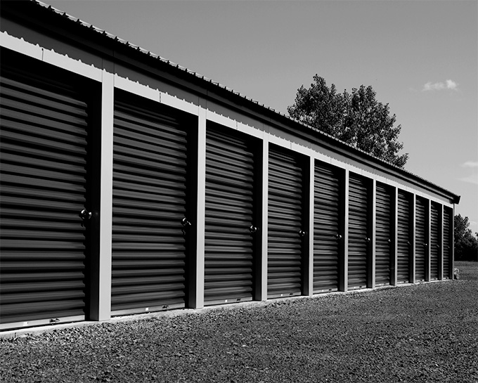 Row of black self-storage units under an open sky
